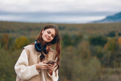 Portrait of young woman standing against mountain