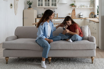 Young woman using phone while sitting on sofa at home