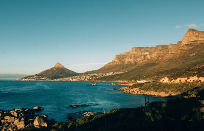 Scenic view of sea and mountains against clear blue sky