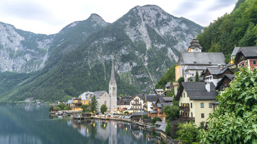 Panoramic view of buildings in town by mountains against sky