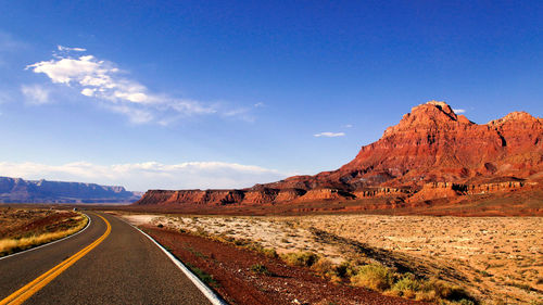 Road leading towards mountains against sky