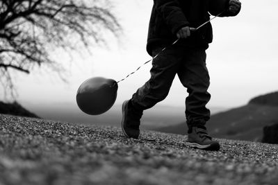 Surface level view of boy walking with balloon on road