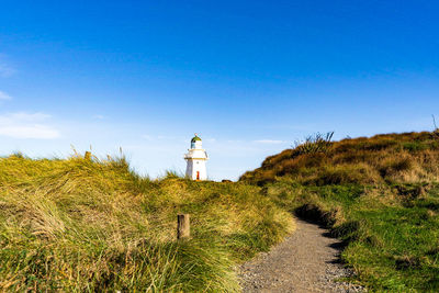 Lighthouse amidst plants on land against sky
