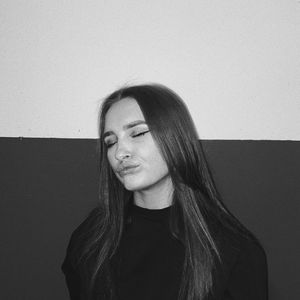 Portrait of young woman standing against wall