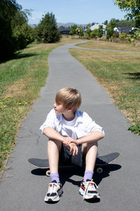 Full length of boy sitting on road
