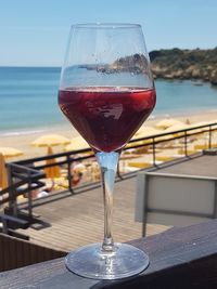 Close-up of wineglass on table against sea