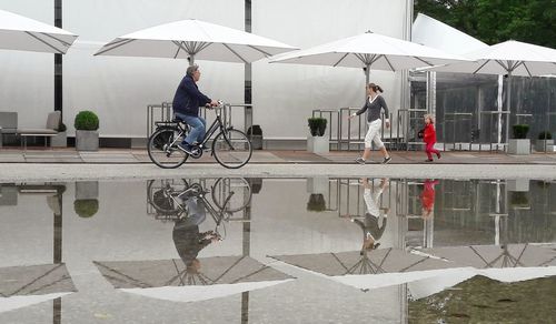 Full length of man with bicycle against sky in city