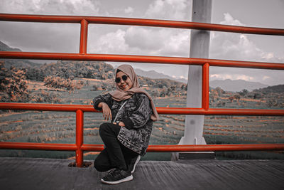 Young woman sitting on railing