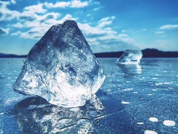 Close-up of ice crystals on rock against sky