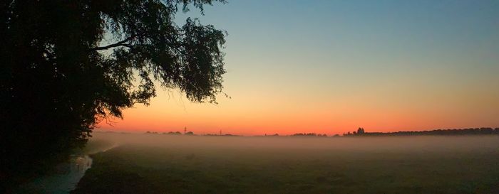 Scenic view of field against clear sky during sunset