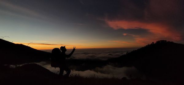 Silhouette people on land against sky during sunset