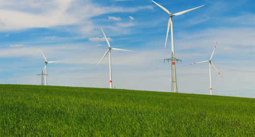 Windmills on field against sky