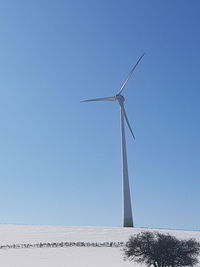 Low angle view of wind turbine against clear blue sky