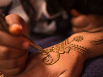 Cropped hand of artist drawing henna tattoo