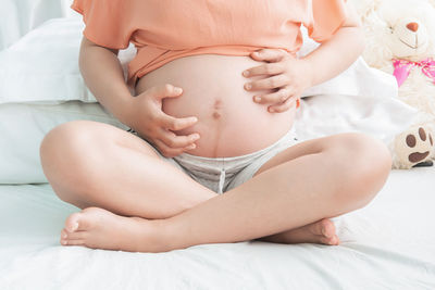 Midsection of woman lying on bed at home