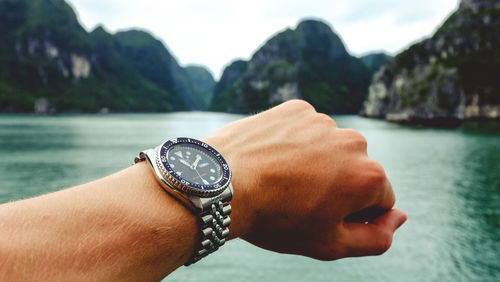 Close-up of hand holding ring over sea against sky