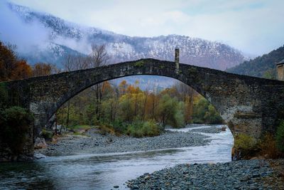 Arch bridge over river against sky