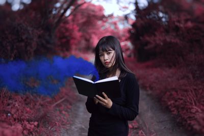 Woman standing by tree against plants