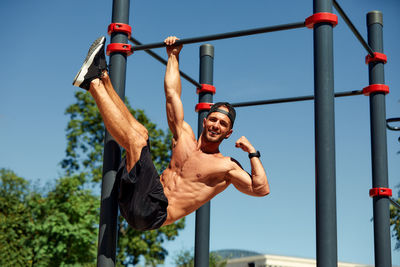 Low angle view of young man exercising against sky