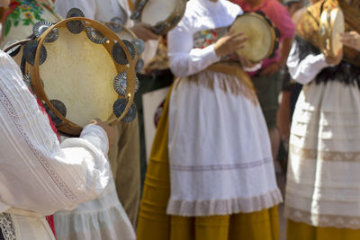 Midsection of people playing tambourines during traditional festival