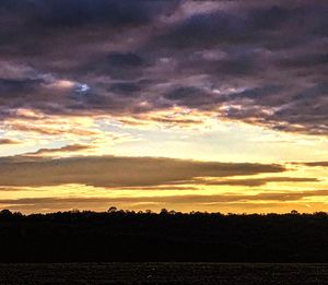 Silhouette landscape against dramatic sky during sunset