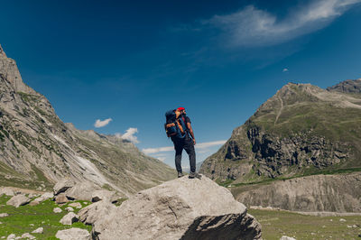 Rear view of man walking on mountain against sky