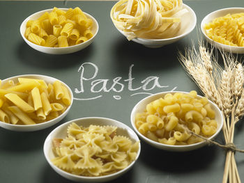 Raw pastas in bowls and text on black background
