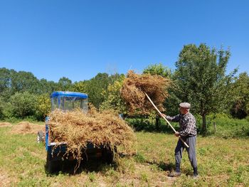 Full length of man working on field against clear sky