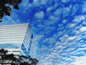 Low angle view of modern building against cloudy sky