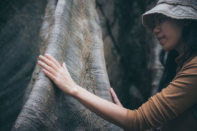 Midsection of woman against tree trunk