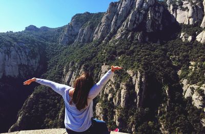 Rear view of young woman on cliff against mountain