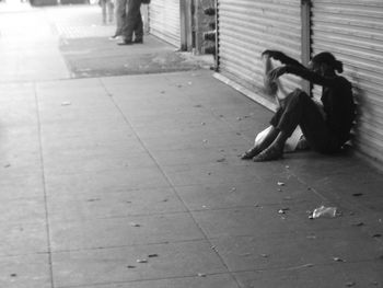 Woman sitting on footpath