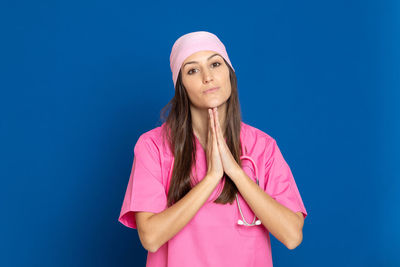 Portrait of beautiful young woman standing against blue background