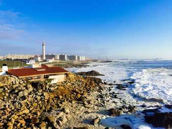 Scenic view of sea by buildings against blue sky