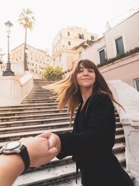 Portrait of beautiful woman against buildings in city