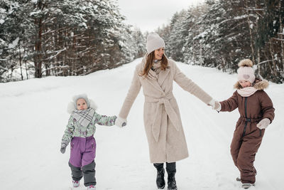 Mother with two daughters walks in a snowy forest on her day off. high quality photo