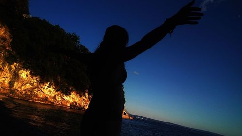 Silhouette woman by sea against clear sky during sunset