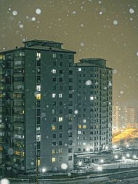 Buildings against sky seen through wet glass window