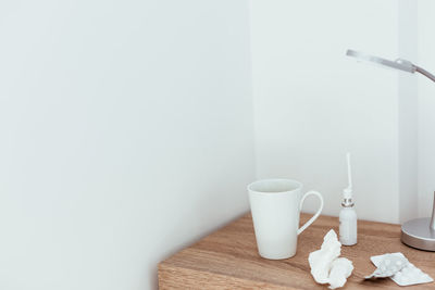 Close-up of coffee cup on table against wall at home