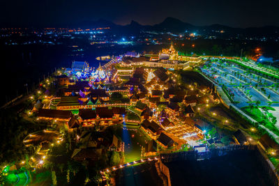 High angle view of illuminated city by buildings at night