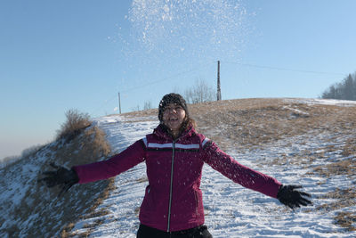 Woman playing with snow against clear sky