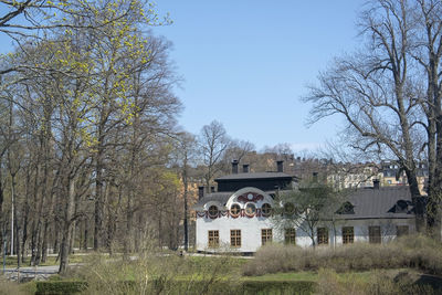 Trees and houses on field against sky