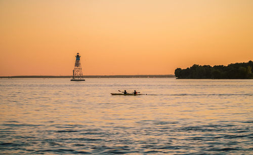 Silhouette boat sailing in sea against clear sky during sunset