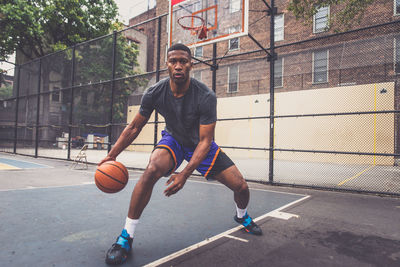 Young man practicing basketball in court