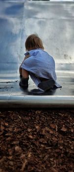 Rear view of boy sitting on land