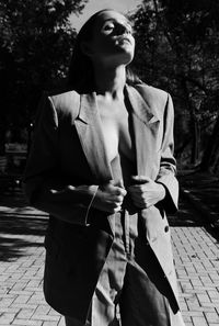 Young woman looking away while standing against trees