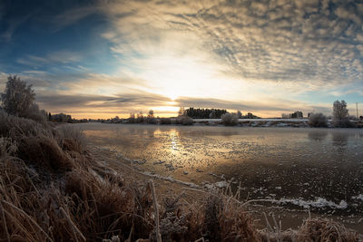 Scenic view of frozen lake against sky during sunset