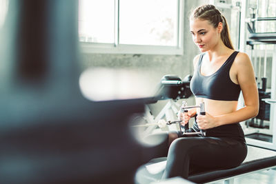 Young woman using phone while sitting on mirror