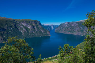 Scenic view of lake and mountains against clear blue sky