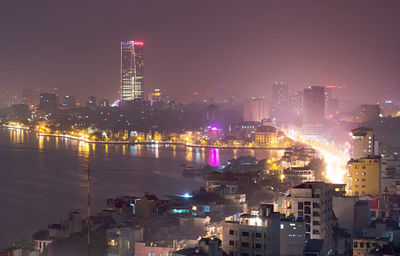 Illuminated buildings in city against sky at night